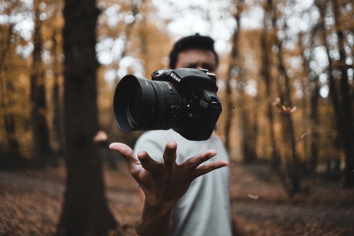 Man holding a floating DSLR camera in the woods